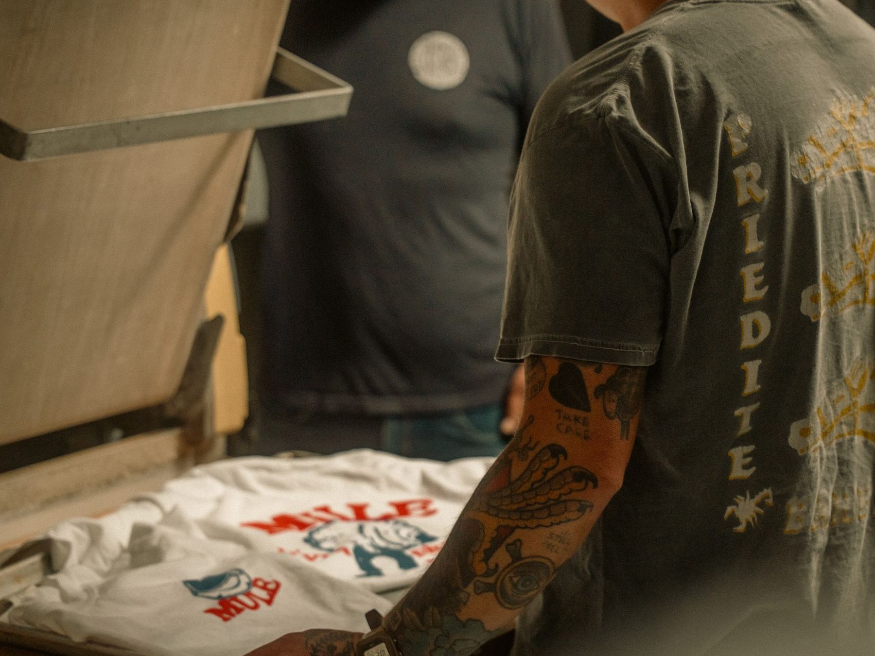 Two people screen-printing a t-shirt in a small studio